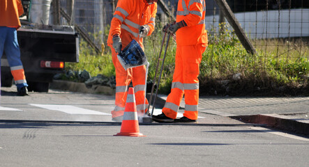 Worker pouring paint from bucket, people working, painting traffic markings on the roads, 