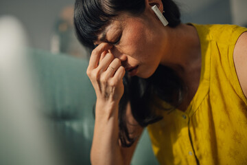 Focused asian woman with headphones working on her laptop at home