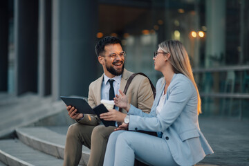 Two business people having a meeting on steps outside office building