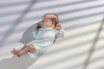 Asian newborn baby with pacifier and lying on the mat