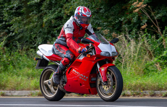 Man riding a red Ducati 916 motorcycle