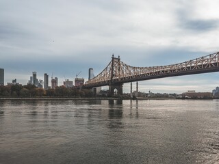 Obraz premium Brooklyn Bridge surrounded by high-rising buildings with cloudy sky on the horizon