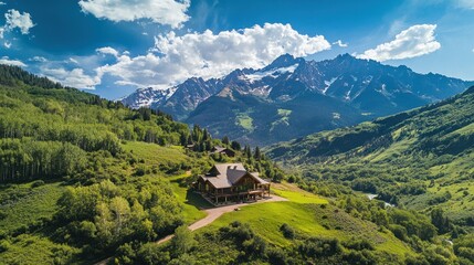 Fototapeta premium A scenic mountain landscape featuring a lodge surrounded by lush greenery and towering peaks.