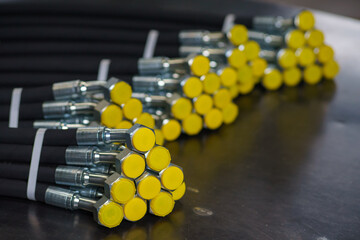 A bundle of new high-pressure hydraulic hoses are lying on a metal table. Hydraulic hoses with...