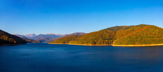 Naklejka premium A beautiful landscape of Vidraru reservoir - Romania and yellowed autumn forest