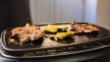 Pork steaks and chicken breast grilling on electric grill