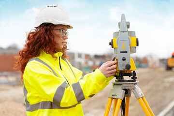 A dedicated surveyor meticulously adjusting equipment at a construction site during a bright, sunny...