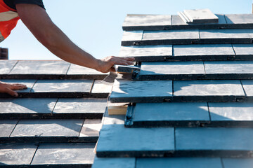 Crafting a sturdy roof with precision tiles under a clear blue sky at a construction site
