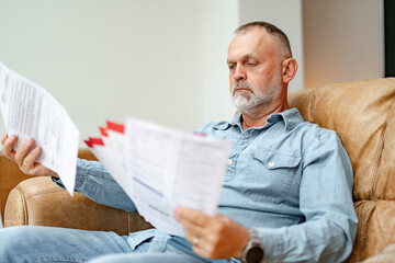 Focused man reviewing important documents in a cozy living room during a quiet afternoon