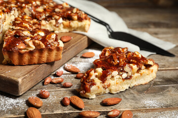 Board of cut sweet tart with different nuts and caramel on wooden background