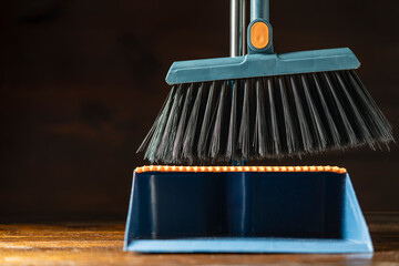 Cleaning plastic broom and dustpan on wooden floor indoors, closeup