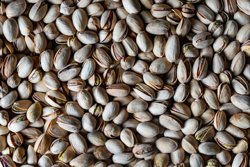 Tasty unpeeled pistachios as background, top view, closeup