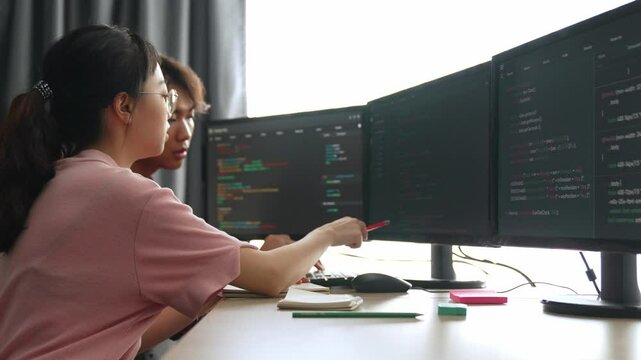 Slow motion back end software developer engineer for computer programming working together on debugging writing computing code, solving complex algorithms display on monitor in office. Burgeoning