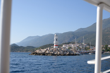 Landscape. A small lighthouse on the coast with a pier near a small town at the foot of the...