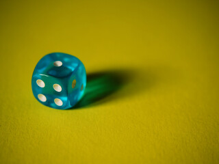 Blue dice on yellow paper background. Cardboard bright background with texture. Concept of luck, testing fate, lottery, decision making. Place for text. Copy space. Rovinj, Croatia - October 4, 2024