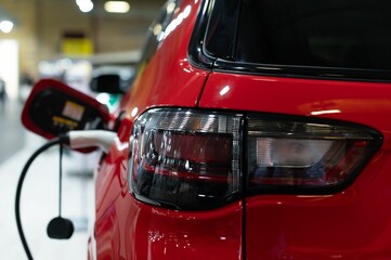 Taillight of a red car while it's getting fueled against a blurry background