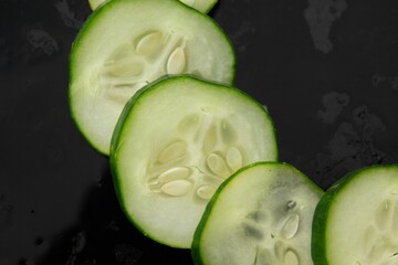Close-up of sliced green cucumber on a black cutting surface