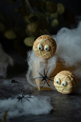 Funny spooky french macarons beige with eyes on dark background with spiders and spider net