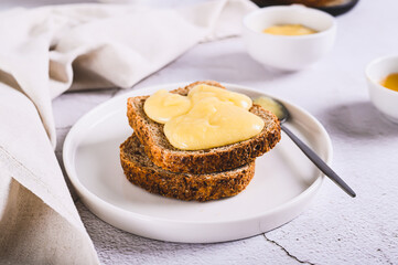 Morning sandwiches on grain bread with honey butter on a plate on the table