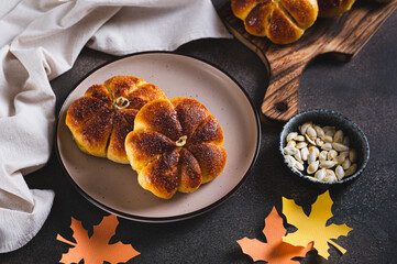 Autumn pumpkin shaped bread buns sprinkled with sugar on a plate on a table