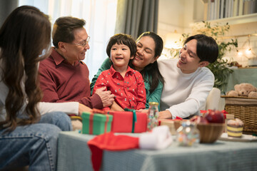 Portrait of Asian parents, child, and grandparents sitting on the sofa in the living room at home.
