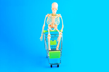 Miniature Skeleton Model in Shopping Cart on Blue