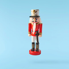 Christmas holliday image, Christmas bauble in shape of a nutcracker falling in the air isolated on blue background