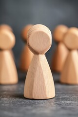 Wooden figurines arranged in a group, emphasizing the central figure on a textured gray background during natural daylight
