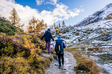 Fototapeta premium People hiking in autumn. Landscape of the mountains, sky and forest. Snowcapped mountain. La Gouille, Evolene, Switzerland..