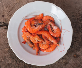 Raw shrimps in porcelain plate on wooden table