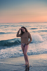 Beautiful girl posing against the backdrop of a sea beach on a warm summer evening. Beautiful bokeh and sea waves in the background