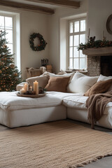 Obraz premium Przytulny salon udekorowany na Boże Narodzenie. W centralnym punkcie jest duża, jasna sofa w kształcie litery L, a obok oświetlona choinka i kominek, na którym stoją ozdoby świąteczne.