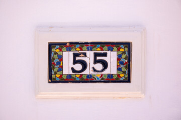 Beautiful house number 55 in Spanish style. House number on a ceramic patterned base in the old...
