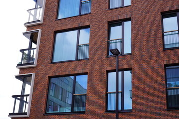 Fototapeta premium Modern red brick building with large reflective windows and minimalistic design. Noblessner, Tallinn, Tallinn, Estonia. August 2024