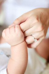 A close-up of an adult hand gently holding a baby's hand, symbolizing care, tenderness, and the bond between a caregiver and a child