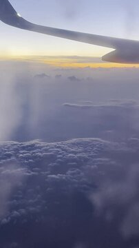Vertical view evening cloudy sky from blurred frozen plane porthole with sunset