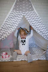 Adorable beautiful happy smiling ginger-haired toddler little girl is playing with her toys sitting in a teepee wigwam © Tina