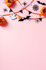 Obraz premium Halloween flat lay with bunting flag garland, orange pumpkins, black spiders, bats, ghosts, and spider webs on a pink background