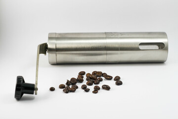 Close up view of manual metallic modern ceramic coffee grinder with coffee beans isolated in white