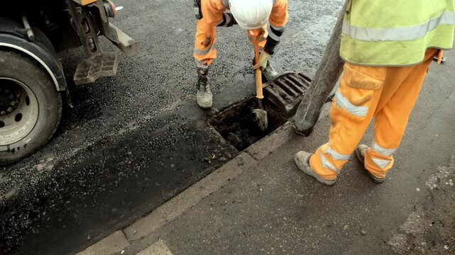 Construction crew repairs drainage system in busy street at dawn, ensuring smooth water flow