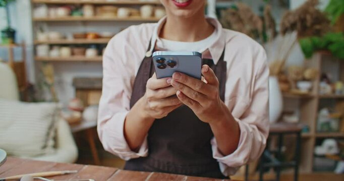 Positive Caucasian female using smartphone with both hands. Typing email or message with fingers on touch screen. Chatting with friend in social media app. Remote communication concept.