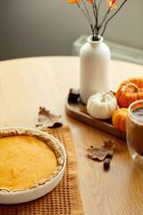 Cozy autumn table setting with homemade pumpkin pie and fall decorations. Thanksgiving, fall concept
