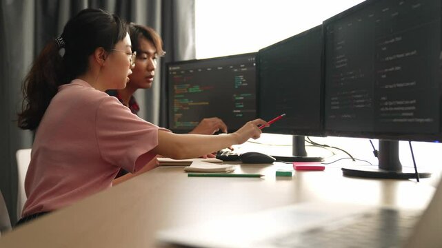 Slow motion back end software developer engineer for computer programming working together on debugging writing computing code, solving complex algorithms display on monitor in office. Burgeoning