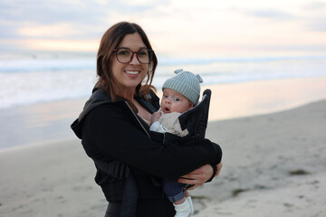 Young mom holding her daughter on the beach.