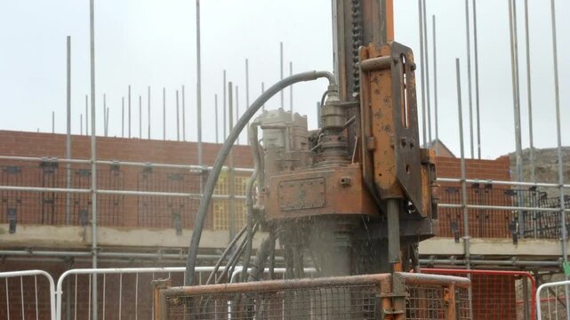 Industrial piling auger drilling rig in action under cloudy sky at a construction site