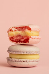 stack of macaroons, one of which is bitten. tasty almond dessert on bright pink background, funny abstraction on taste theme