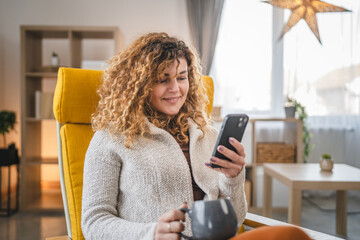 One woman with curly hair at home use mobile phone smartphone sms texting or browse internet