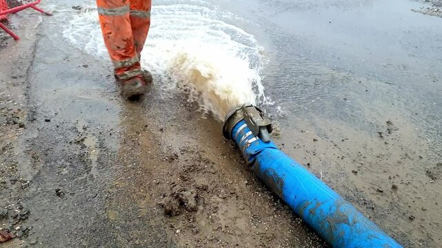 Builder fighting flooding and pumping out water after heavy rain