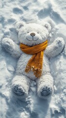 Fluffy white teddy bear dressed in a bright orange scarf lies cheerfully on fresh, untouched snow, creating snow angels
