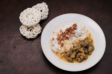 Gulai Kambing or Lamb Curry with rice on a white palte and krupuk, Traditional Javanese mutton curry soup.